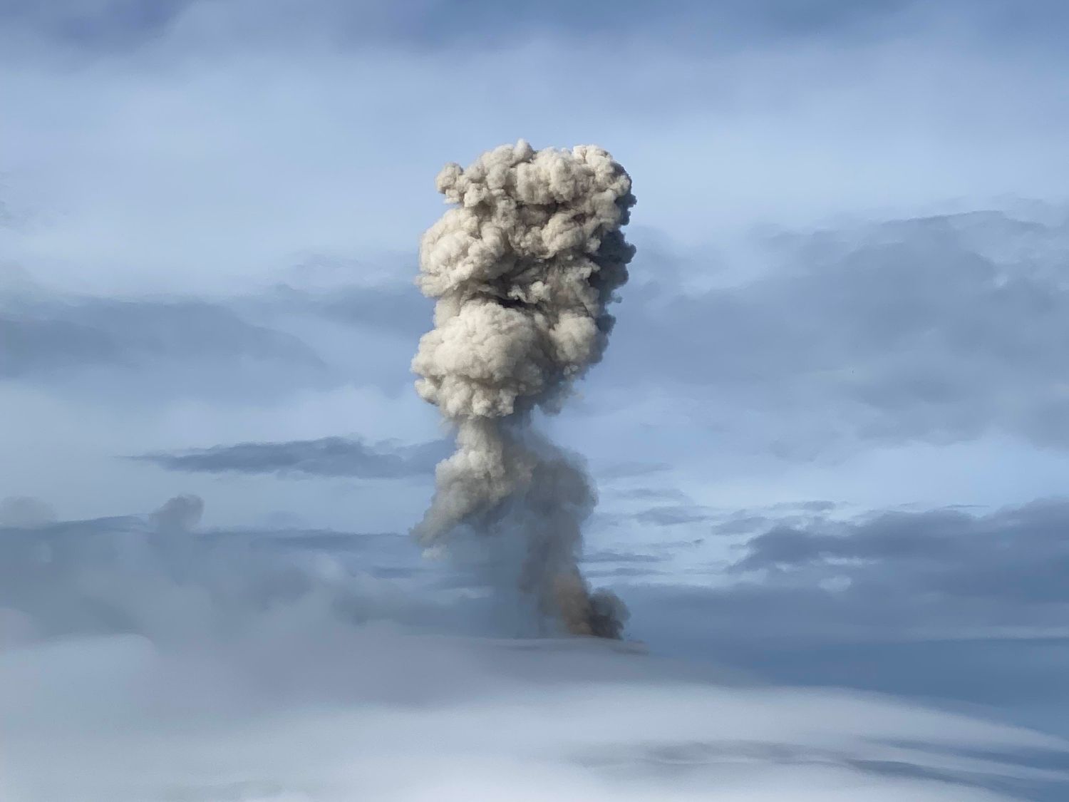 Ash plume rising from an erupting volcano