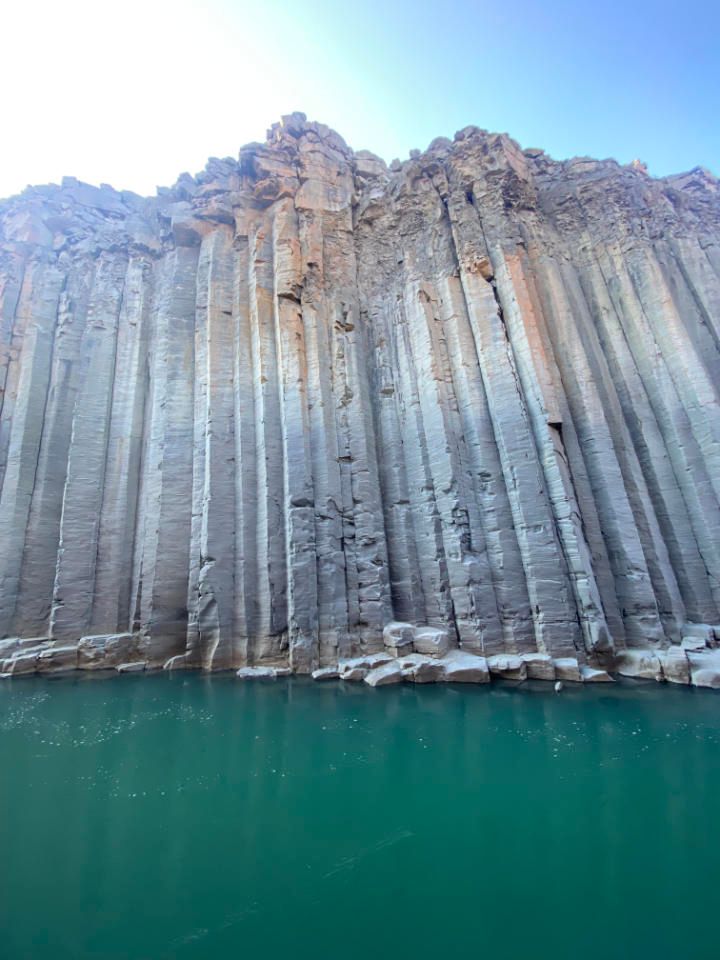 Columnar basalt cliff face rising above turquoise water
