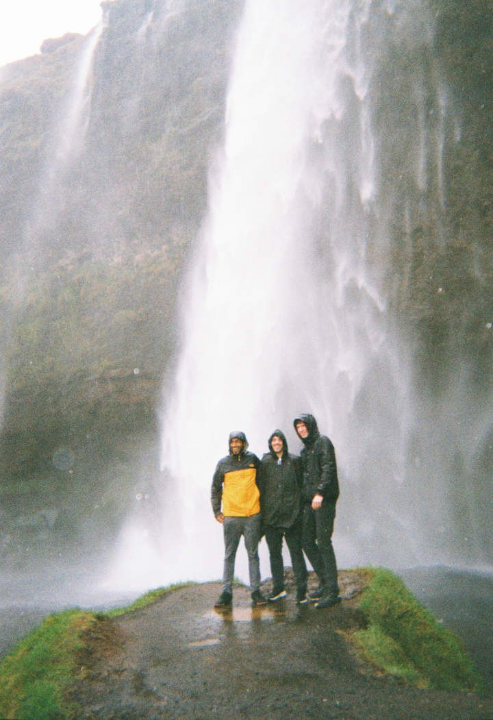 Three friends standing at the base of Gljúfrabúi waterfall